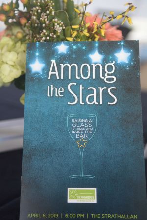 Photo shows program book of Among the Stars in front of floral arrangement